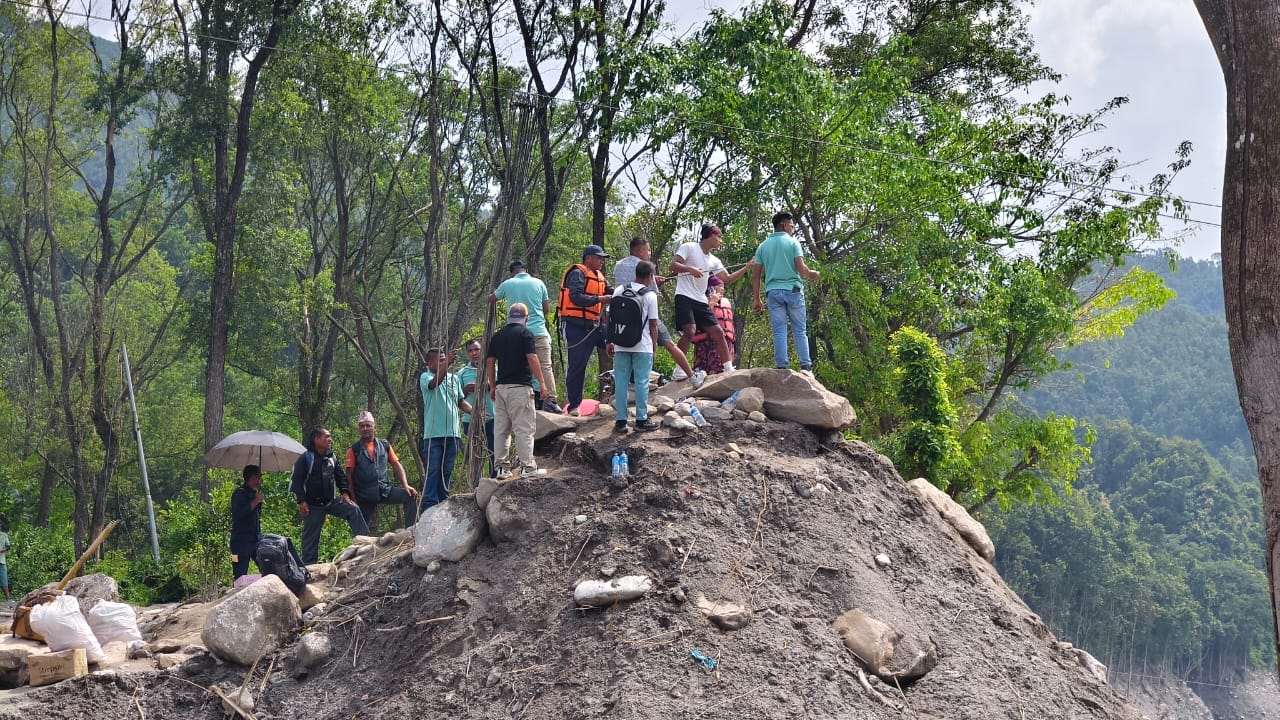 People standing on a mound of debris and silt above the valley