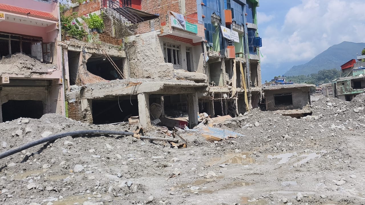 Shopfronts along a street buried to the first floor in mud and rubble