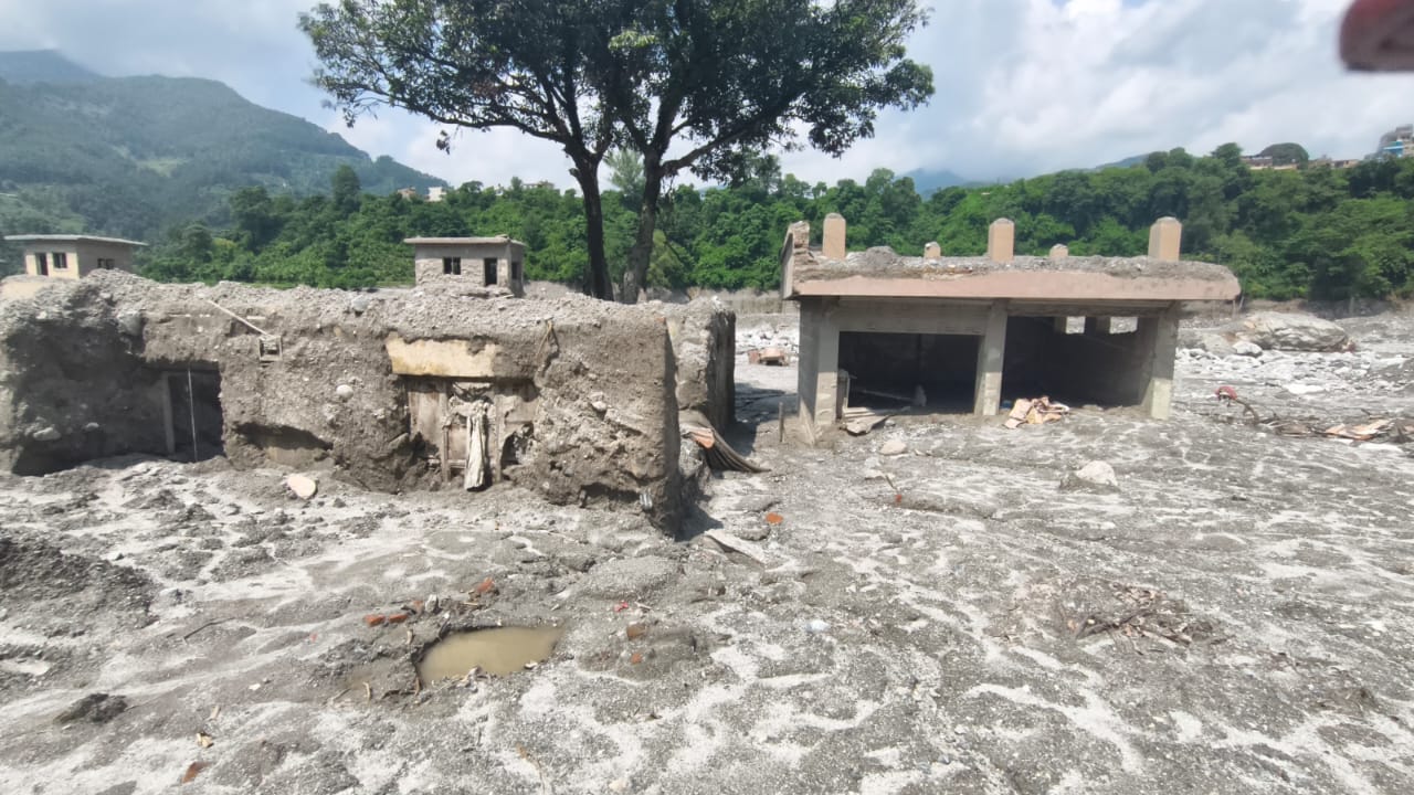 Small houses filled with silt, standing in the grey plain left by the flood